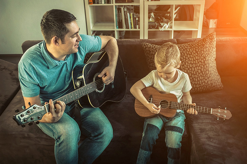 Father teaching his son to play on guitar 