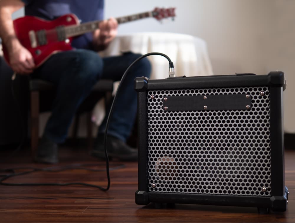 Man playing electric guitar using amp