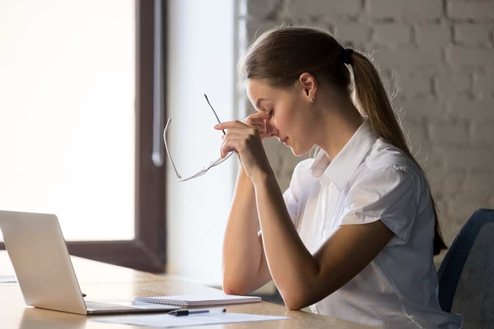 Woman looks tired with her laptop on table