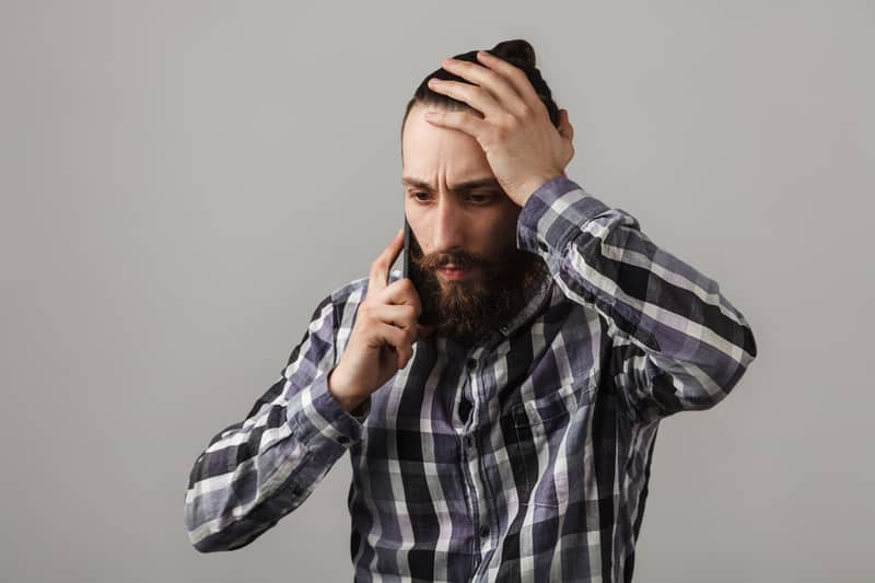 Bearded handsome sad man is talking by phone