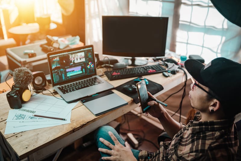 The content creator using mobile working with the laptop