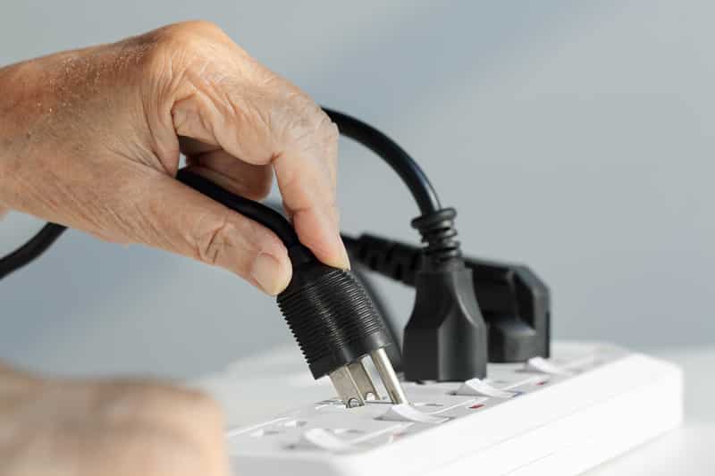 Elderly hand plugging into electrical outlet