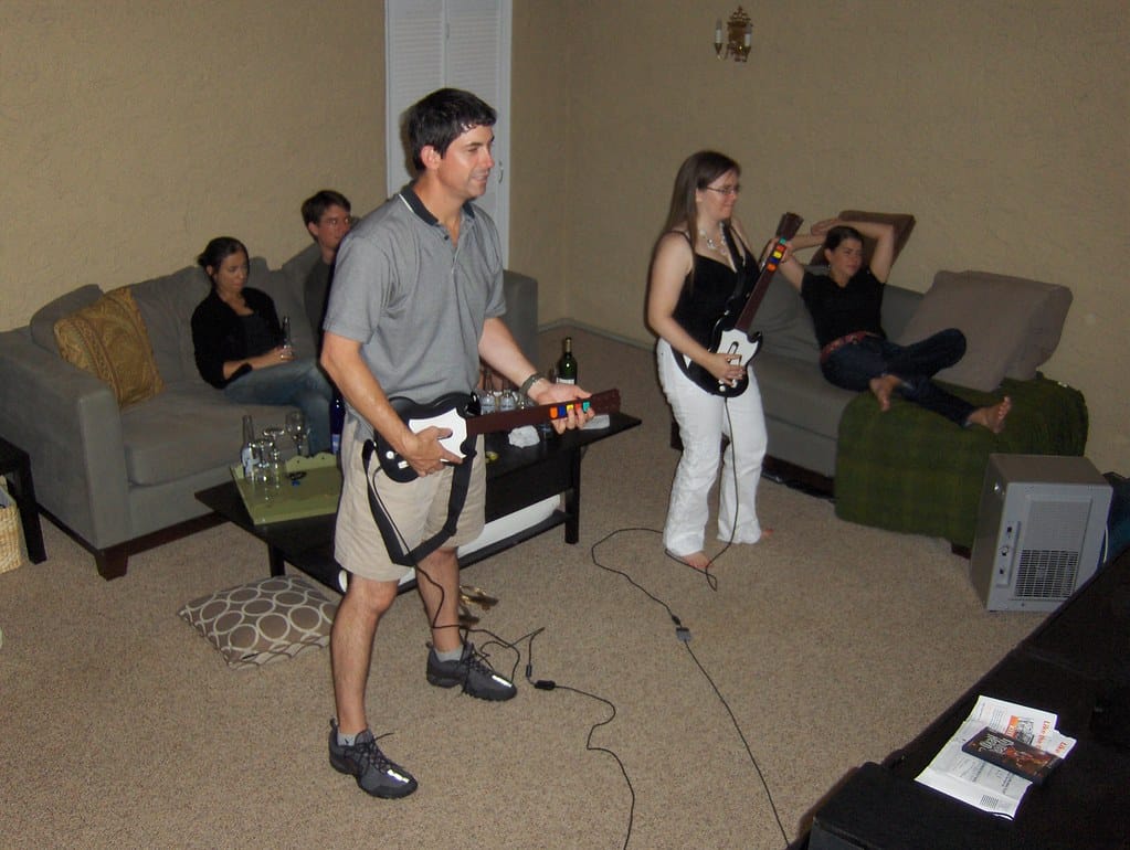 Friends playing guitar hero in living room