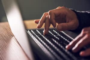 hands typing laptop keyboard