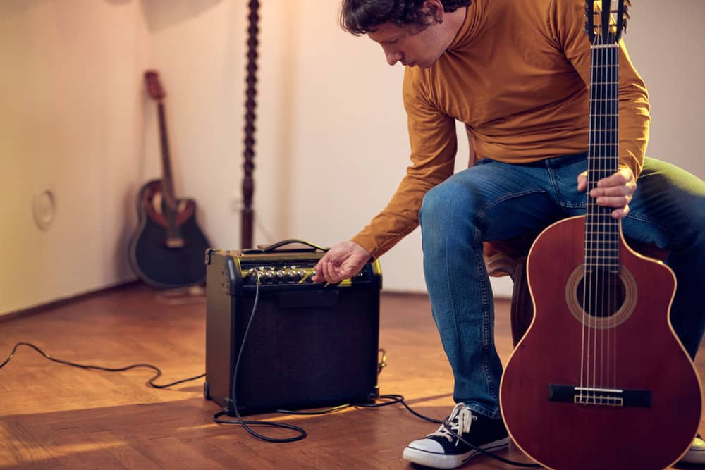 Male musician playing acoustic guitar on the amplifier