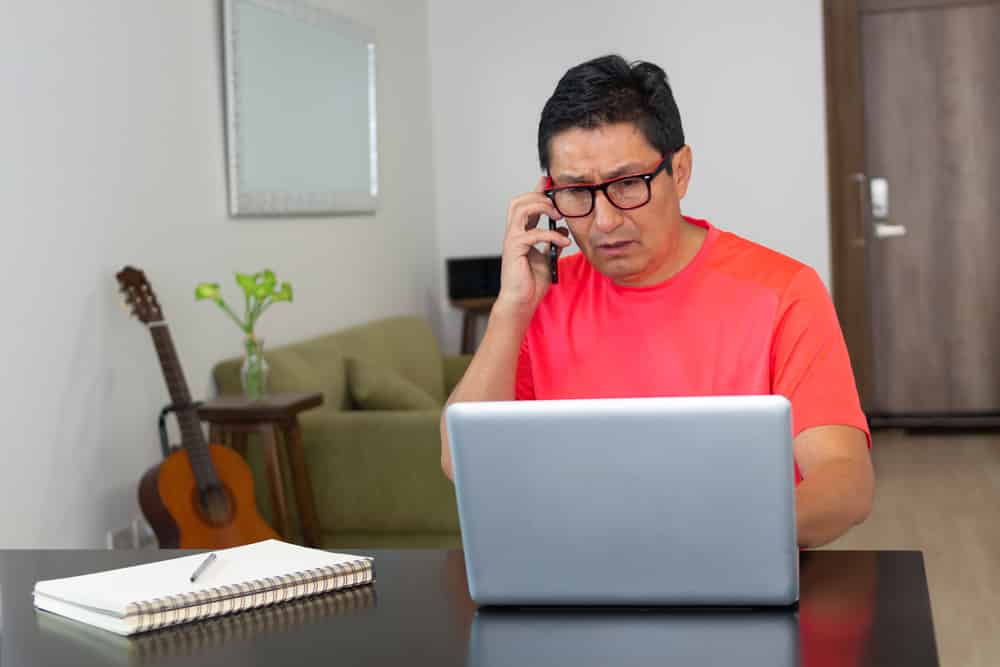 Man who is in his living room working talking on the cellphone