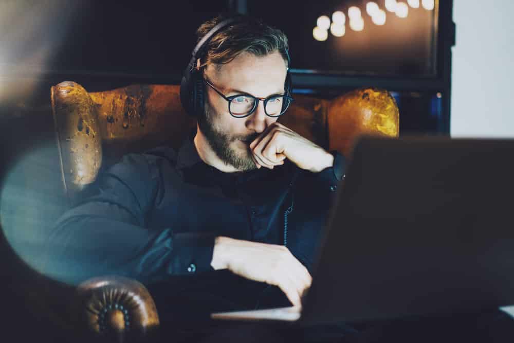 Man sitting in vintage chair listening music laptop night