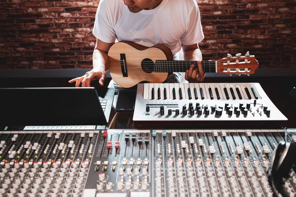 Asian male songwriter playing acoustic guitar for making music