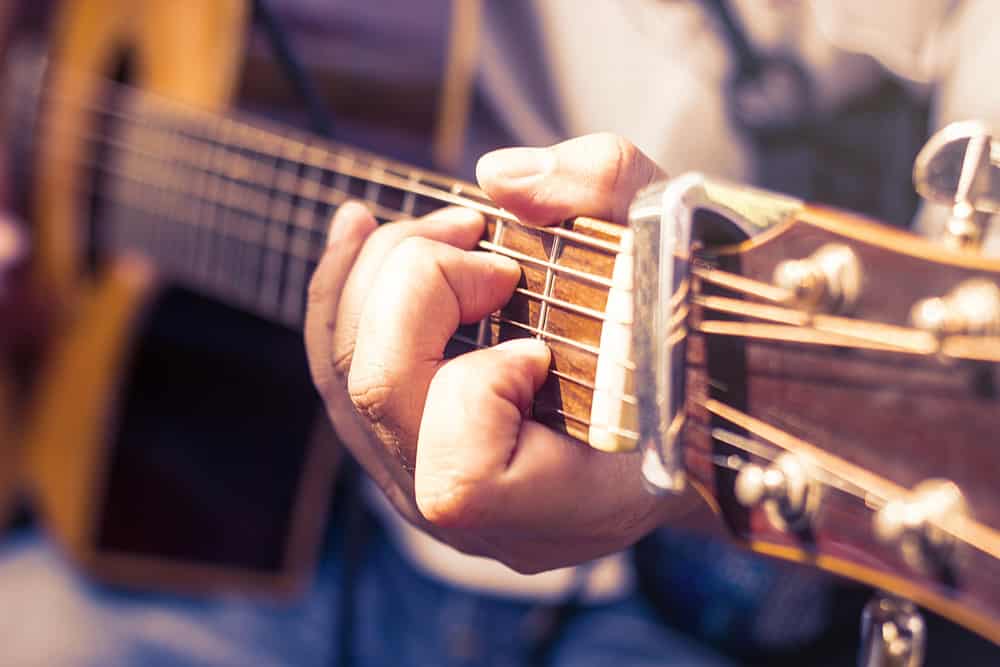 closeup of man's hands playing acoustic guitar