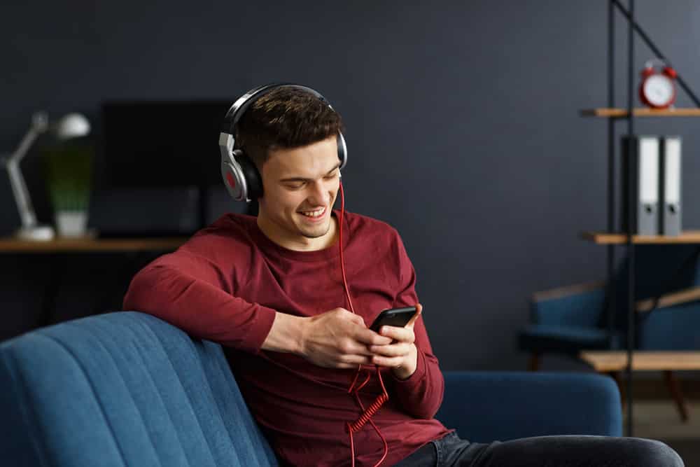 Young man in headphones listening music on smart phone
