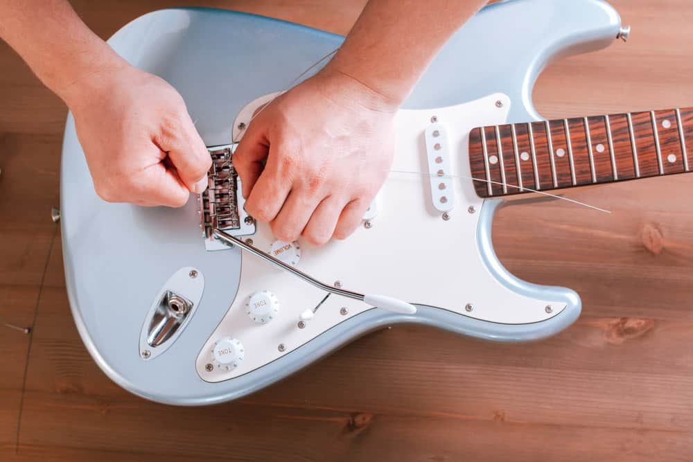 Guitar master restringing electric guitar