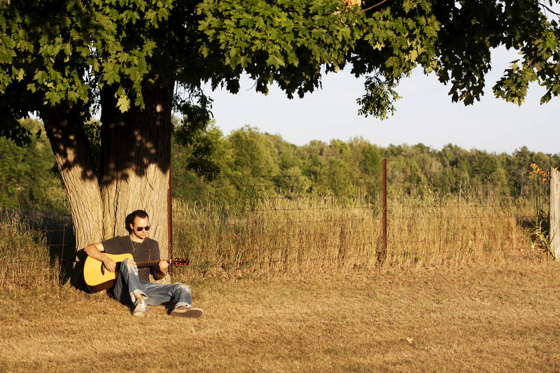 Guy Playing Guitar at Sunset under Maple Tree