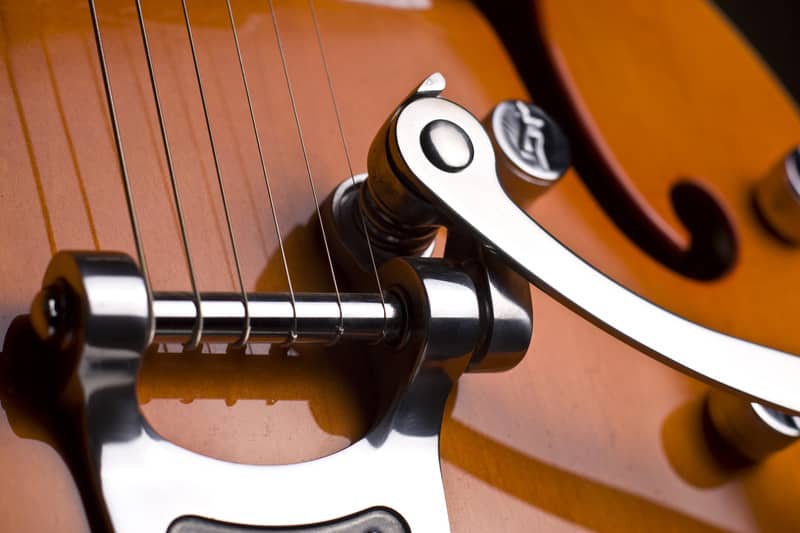 Vertical close up of the chords of an orange electrical guitar