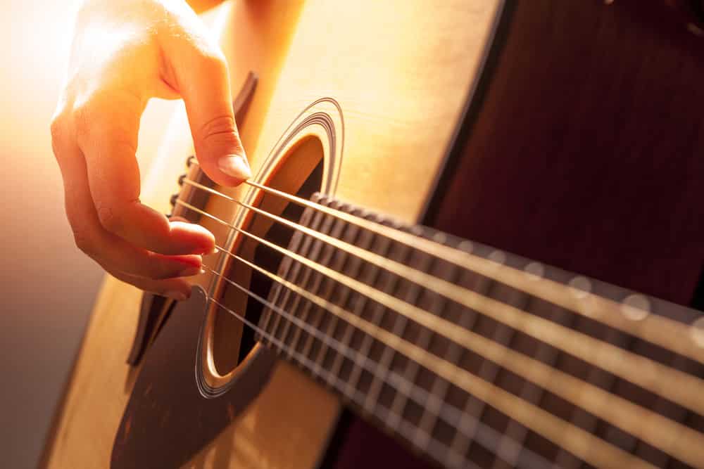 woman's hands playing acoustic guitar