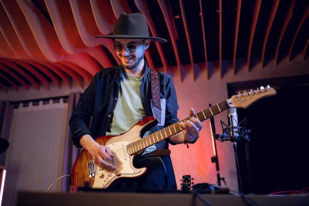 Young man practicing in playing guitar at modern studio