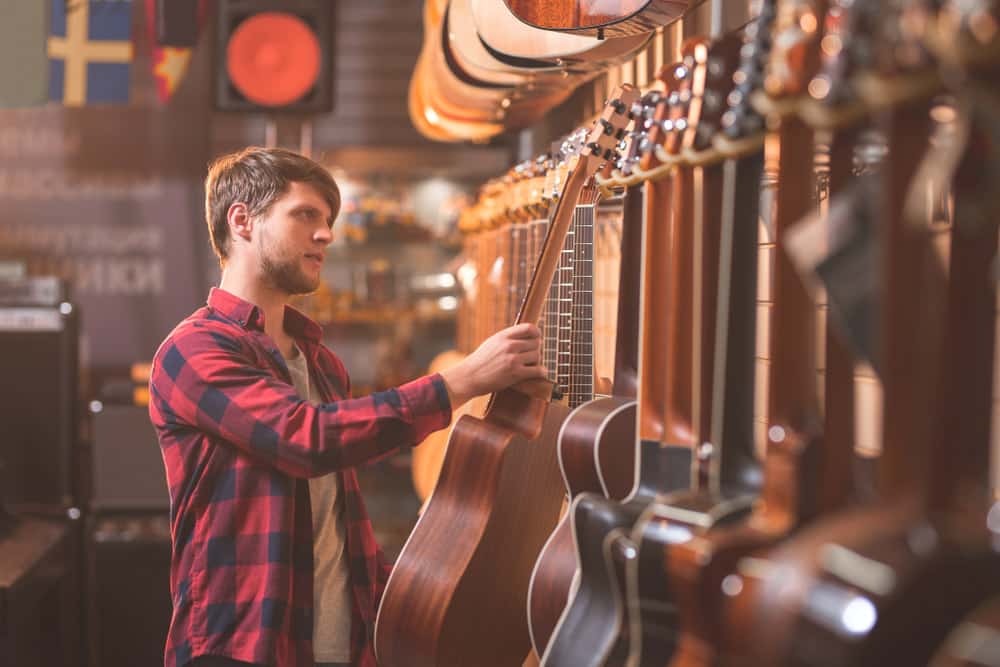Young musician choosing a guitar in a music store