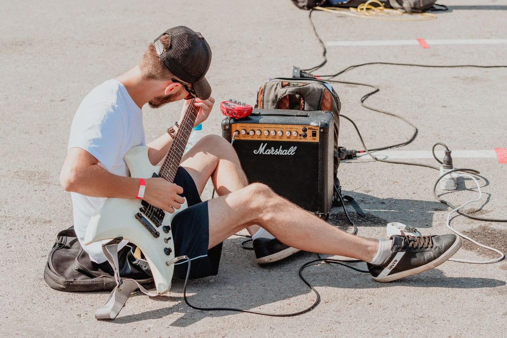 A street guitarist tunes up a Marshall guitar amp before performing