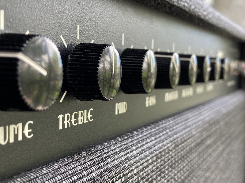 Close-up black treble knob volume on the control panel of the boutique electric guitar amplifier