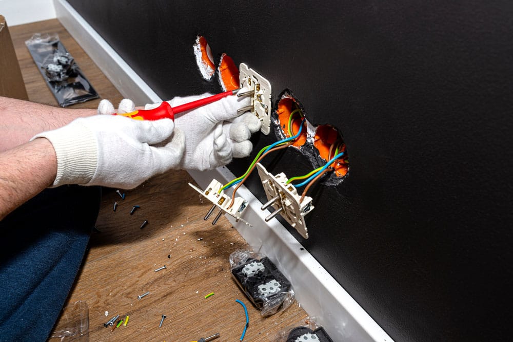 An electrician uses a red screwdriver