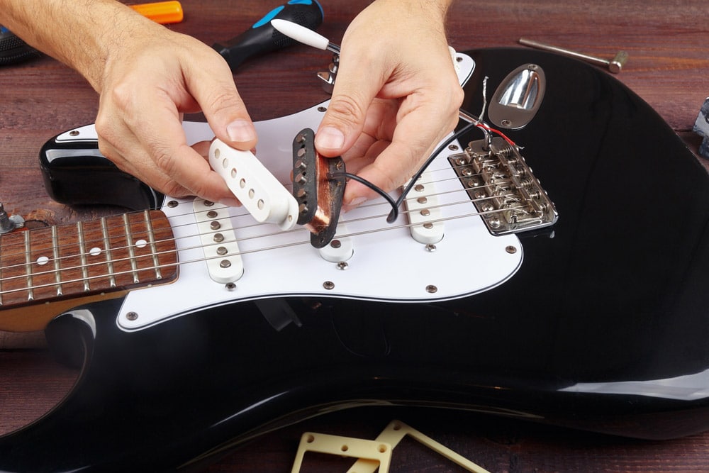 Guitar repairman selects a pickup for replacement on electric guitar
