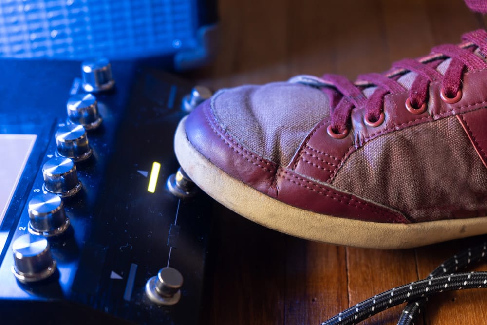 Guitarist pushing the guitar pedal buttons with foot