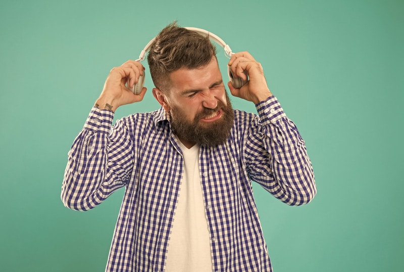 caucasian guy with beard and mustache dont like loud music in digital earphones