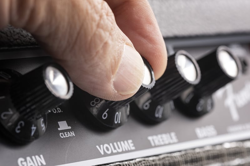 Hand turning up the volume of a guitar amplifier