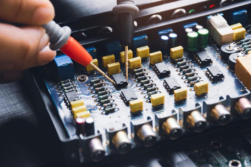 Technician checking ic on circuit board with multimeter