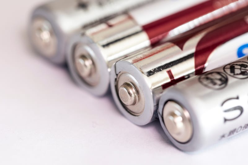 Triple A or AAA batteries lying on an almost white surface