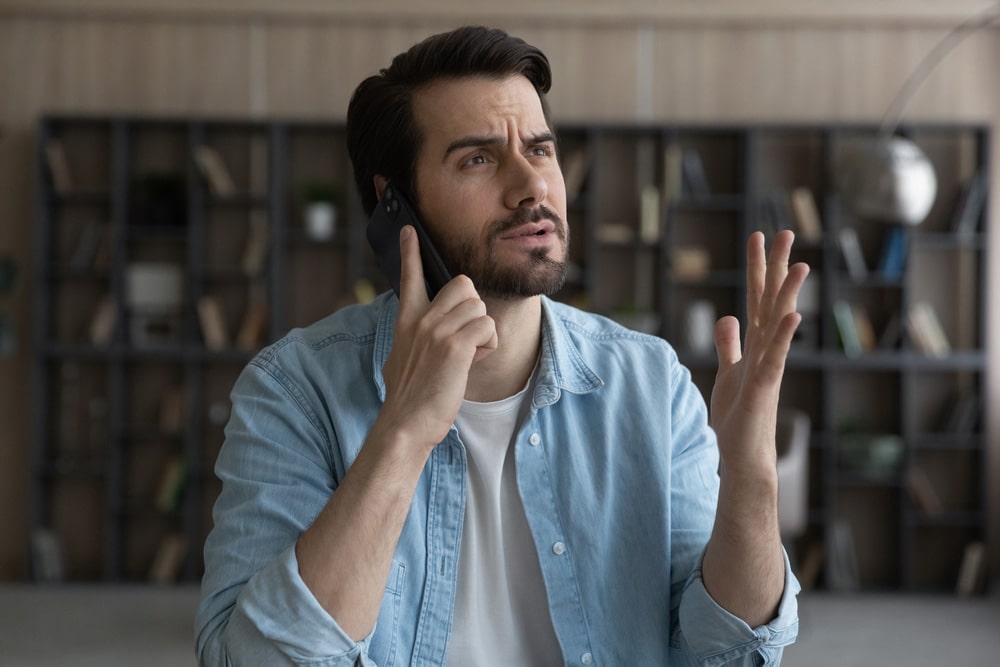 Unhappy young Caucasian man talk speak on smartphone 