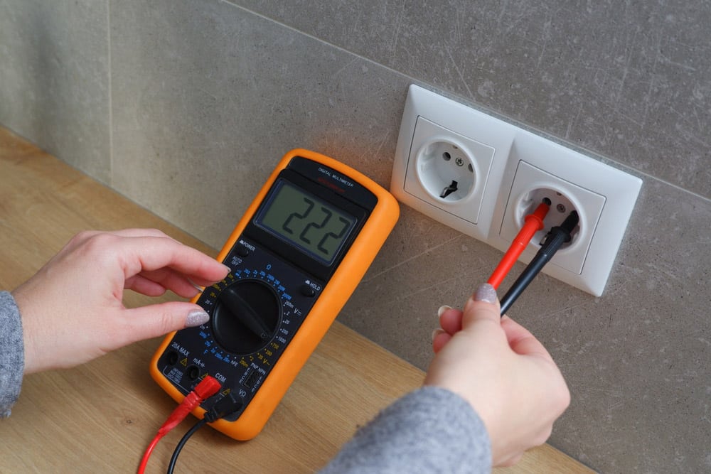 Woman with a multimeter check the voltage of the electrical network