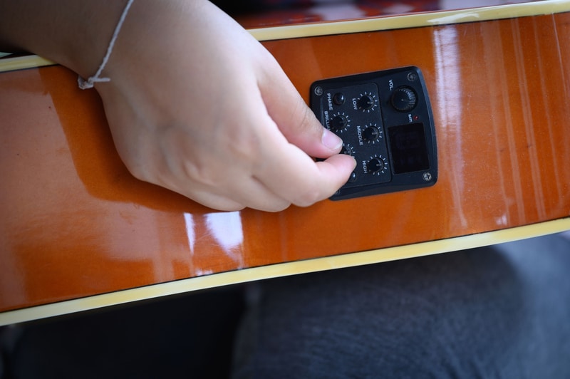 Woman`s hand holding of an acoustic guitar equalizer