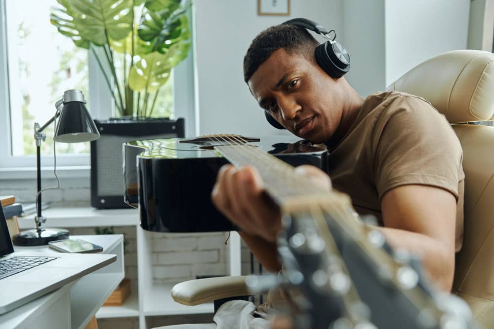 Young African man examining acoustic guitar