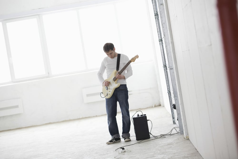 Young man playing electric guitar in empty warehouse