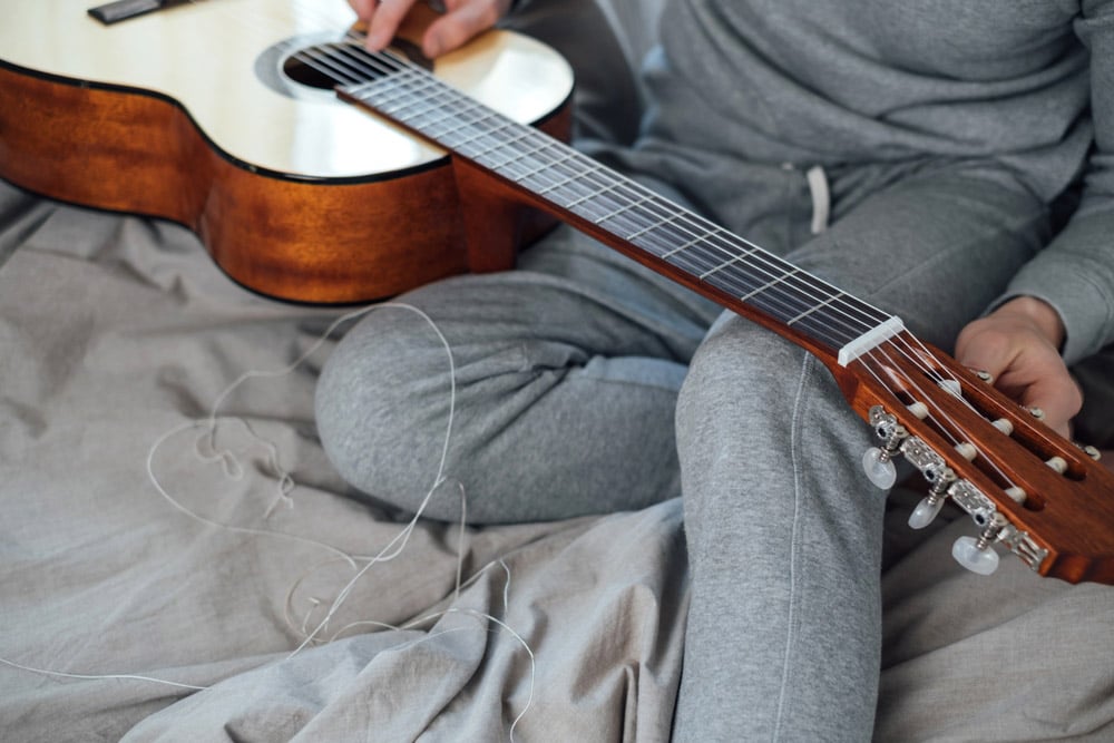 A man pulls a new string on a guitar