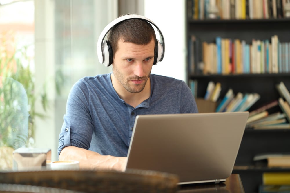 Adult man wearing headphones using a laptop