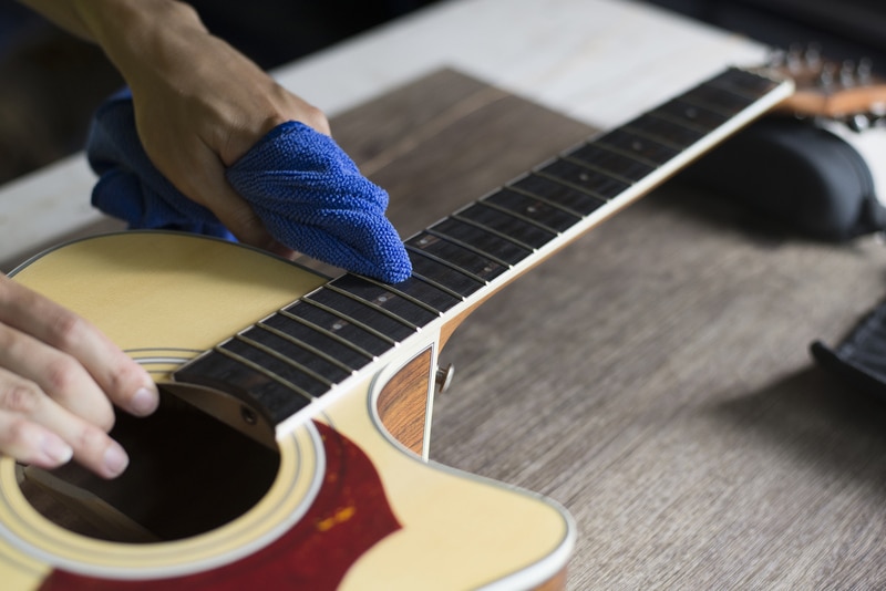 Guitar repairer is cleaning acoustic guitar