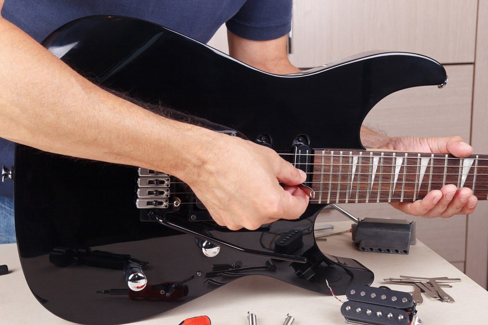 Guitar repairman checking the radius of strings electric guitar