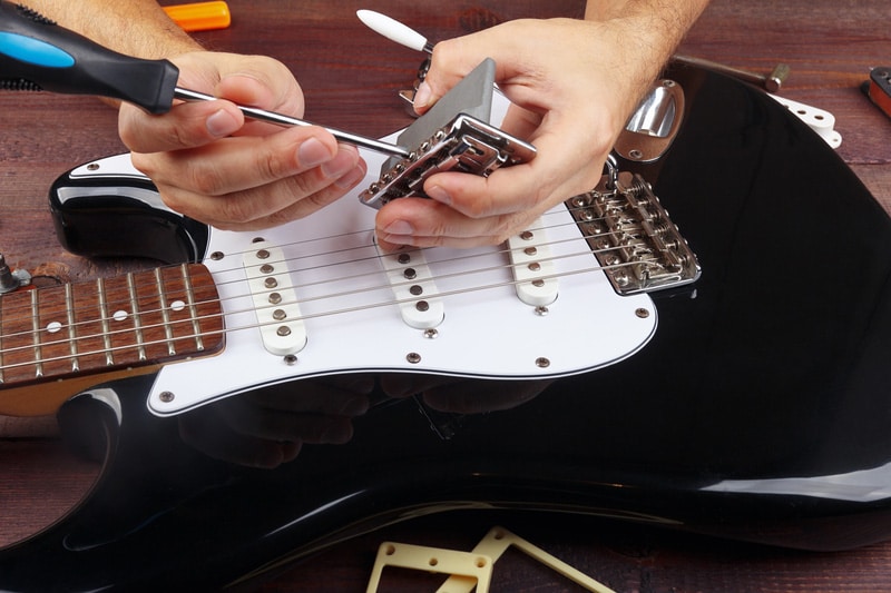 Guitar technician repairs tremolo bridge from electric guitar