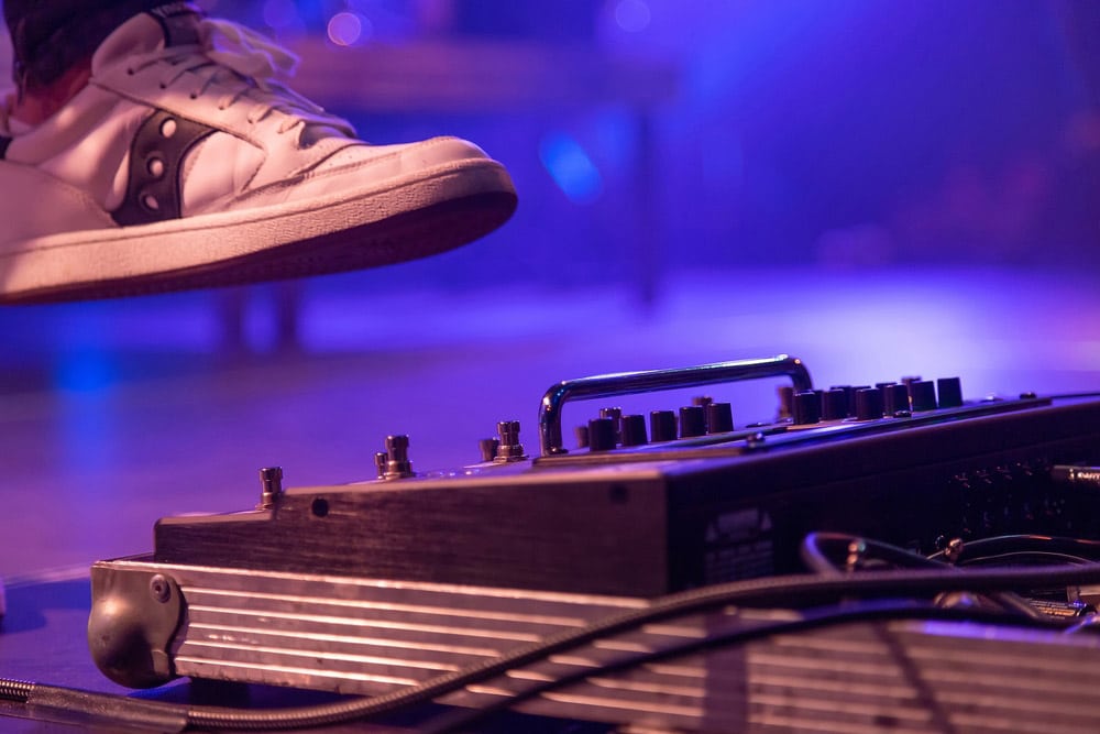 The guitarist kicks the switch on the effects processor