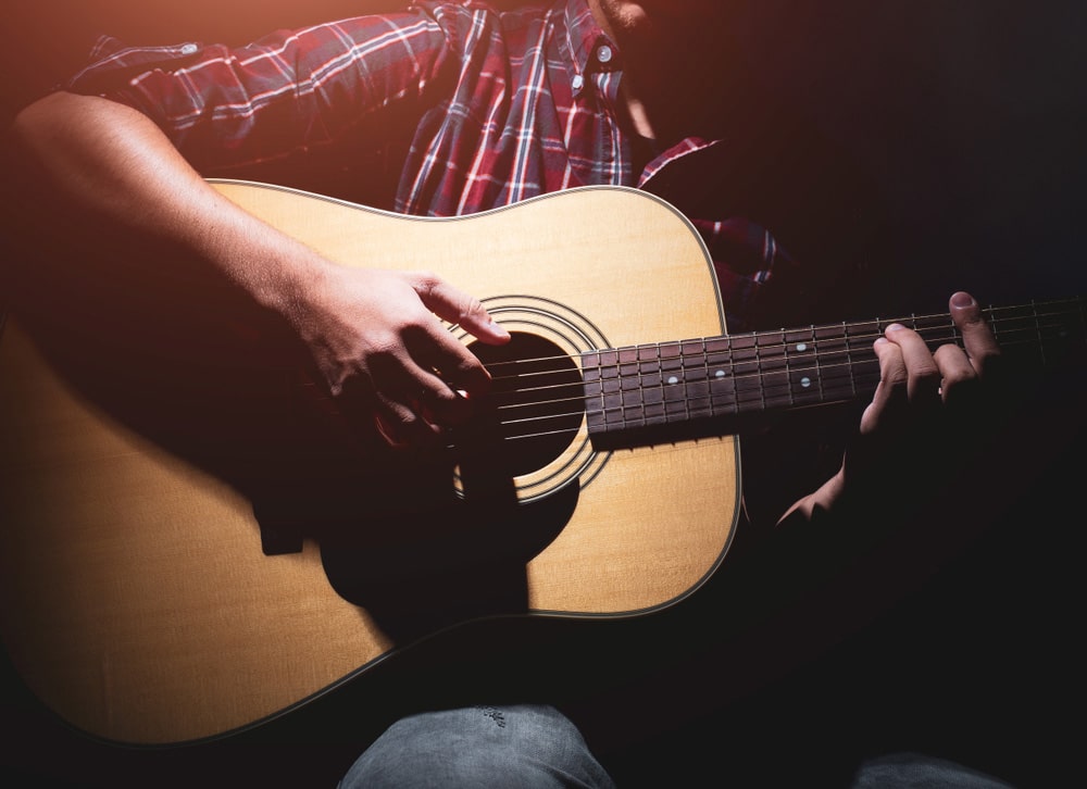 Guitarist plays on acoustic guitar on the stage
