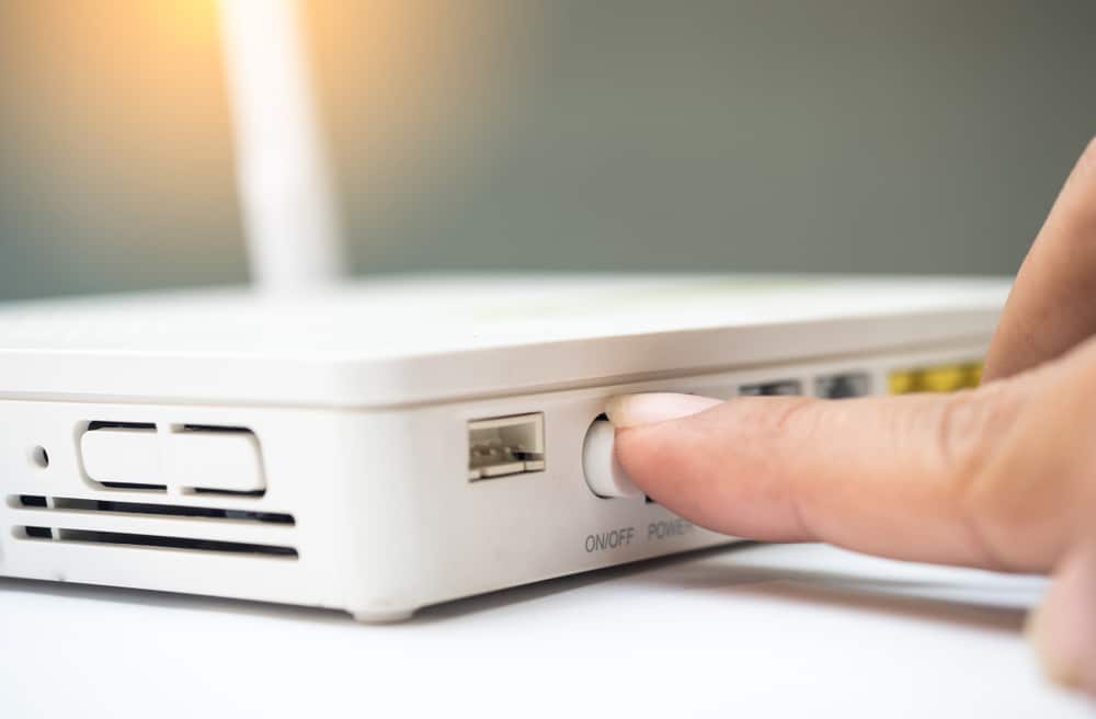 Man press with his finger on button on Wi-Fi Router