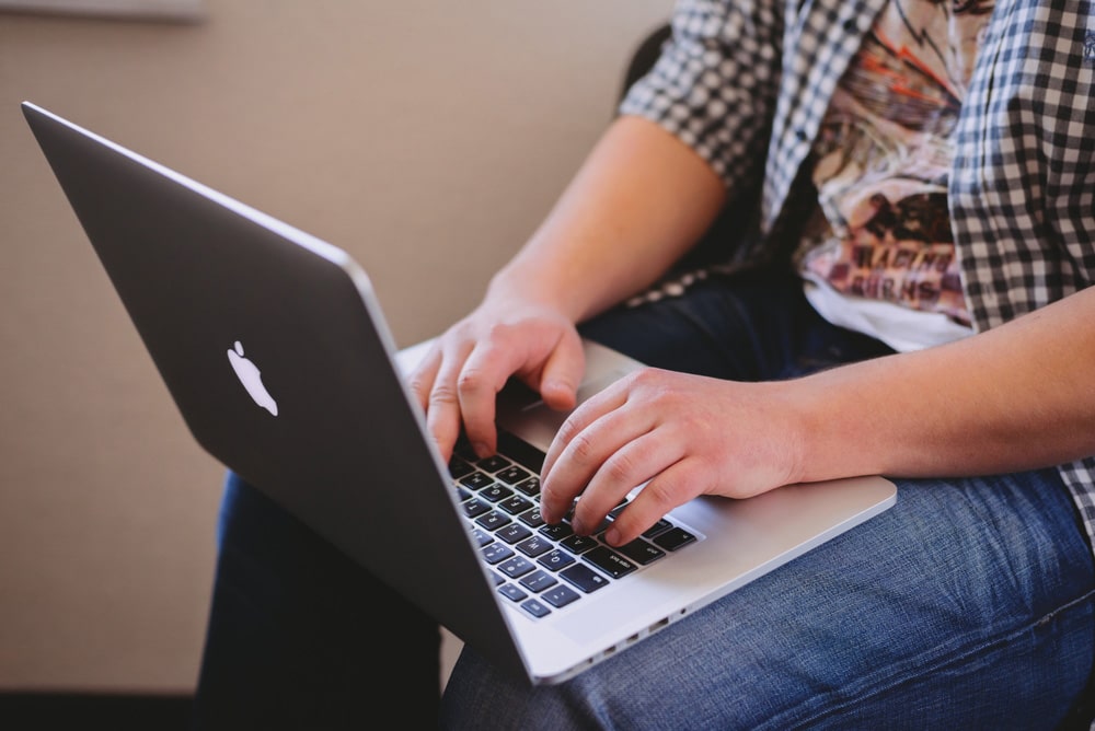 Man typing on Apple MacBook keyboard