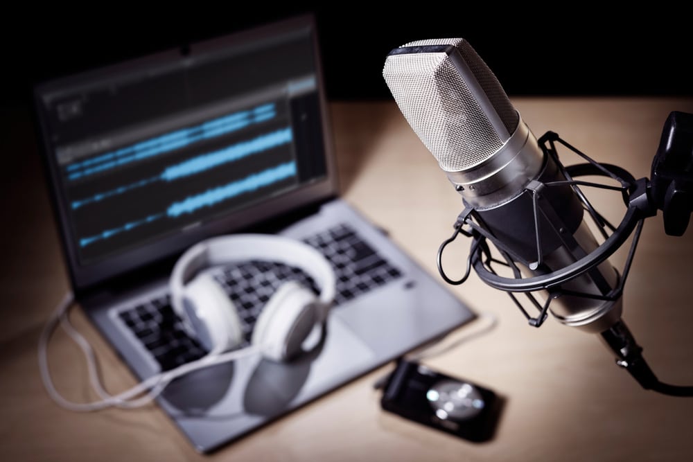 Podcast microphone, laptop computer camera and headphones on desk in recording studio