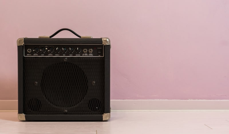 Portable electric guitar amplifier isolated in front of a stone wall