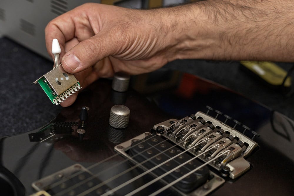 Holds in his hand the new switch of an electric guitar