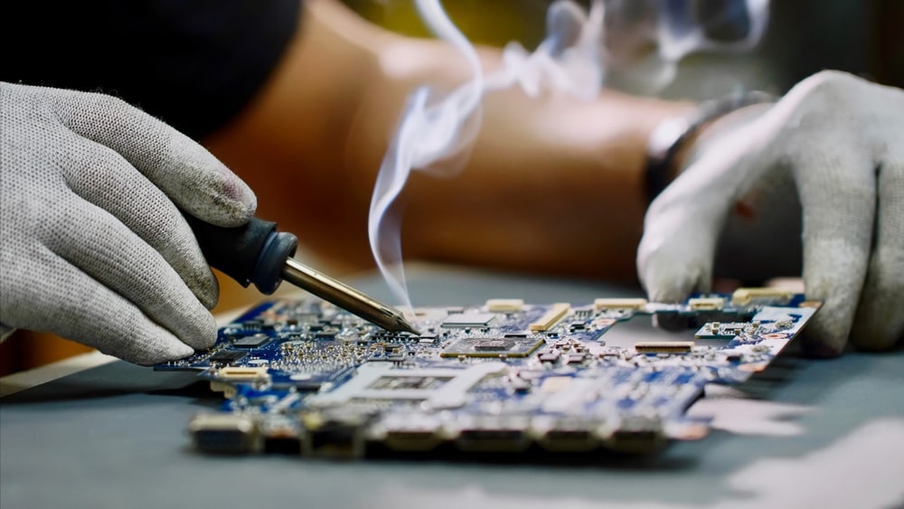 Repairman in gloves is soldering circuit board