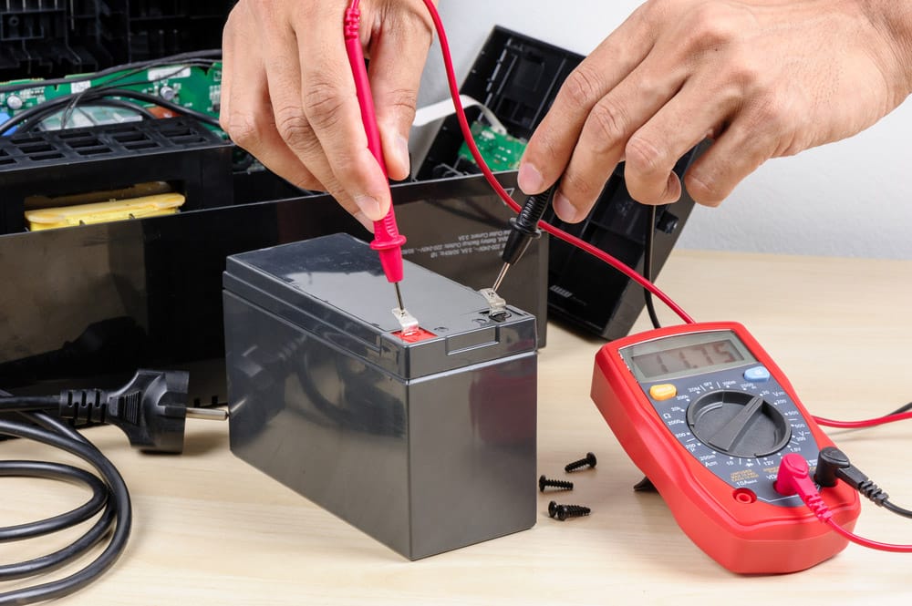 Technician measuring the voltage of battery for UPS 