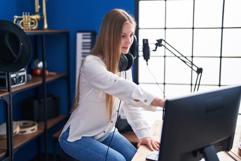 Woman artist composing song using computer at music studio