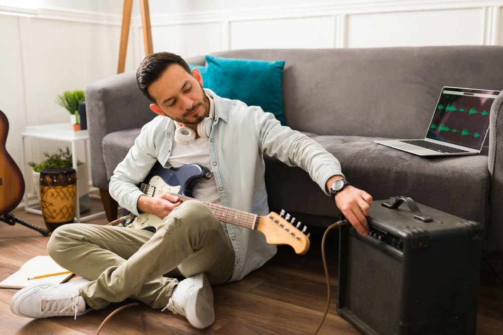 Young man using an amplifier while playing the electric guitar